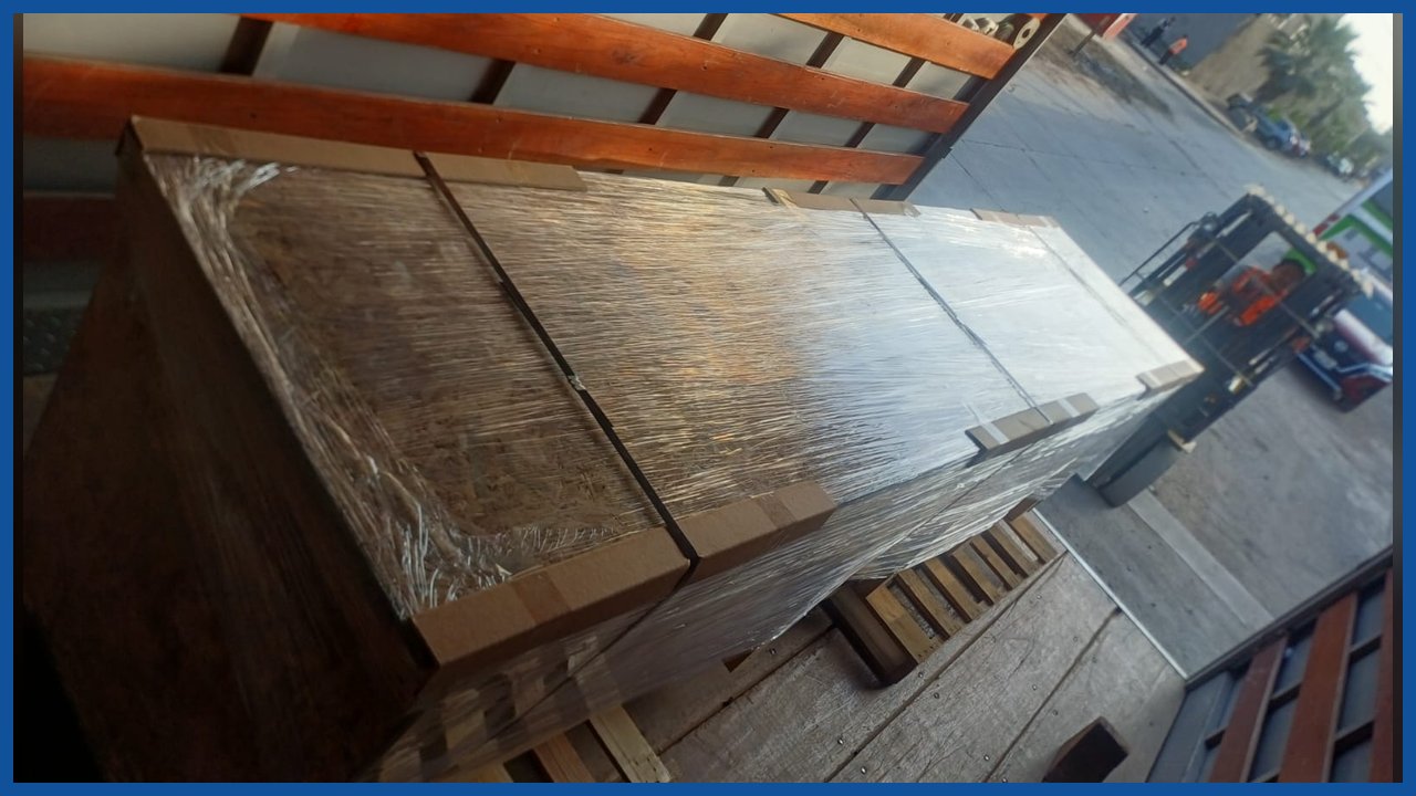 Cajones de madera embalados con film sobre la plataforma de un camión, junto a un montacargas